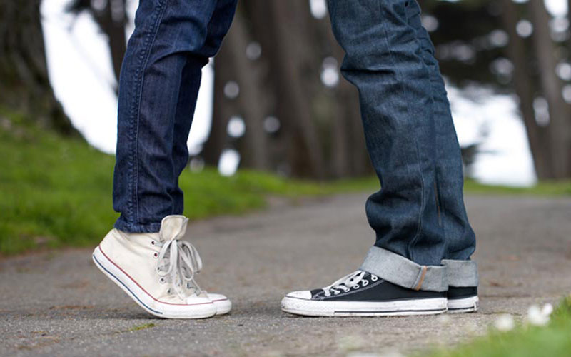 Image of couple wearing converse kissing.