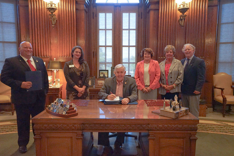 Ceremonial signing of HB-115 in the Governor's Office. From left: Rep. Bennie Cook (R-Houston); Jennifer Carter Dochler; Gov. Mike Parson (seated); Kyna Iman, Government Relations for the Missouri Nurses Association (MONA); Rep. Gretchen Bangert (D-Florrisant); Rep. Travis Smith (R-Dora).