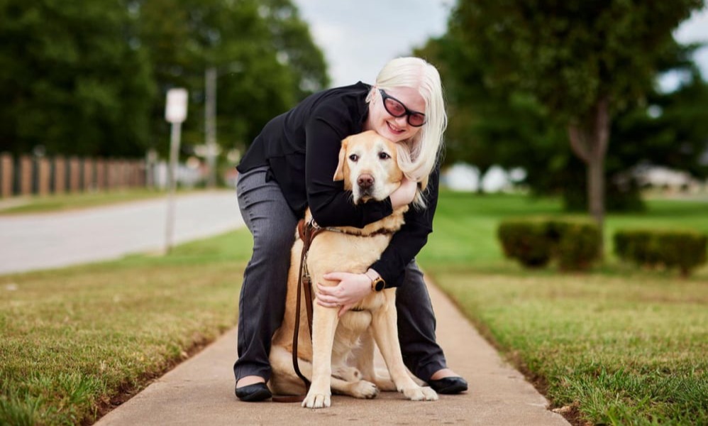 New MFH iconic photo of woman with dark glasses bending to embrace support dog