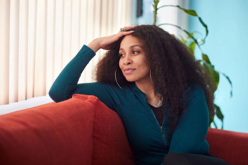 New MFH iconic photo of Black woman sitting on couch looking toward a window in a contemplative manner