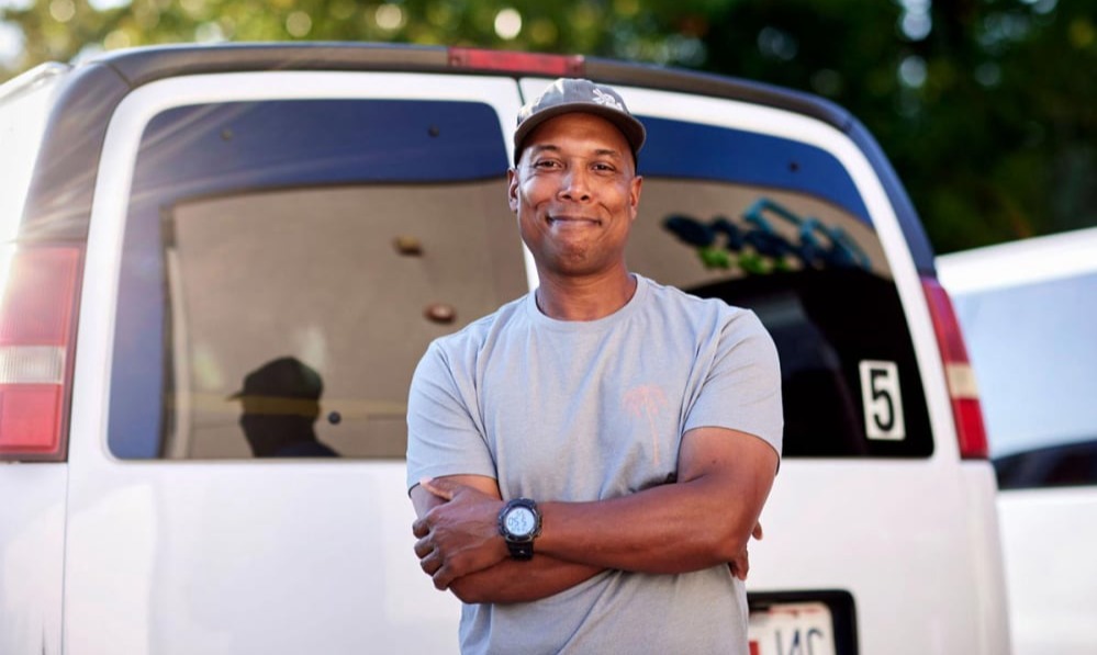 New MFH iconic photo of smiling brown-skinned man standing in front of white work van