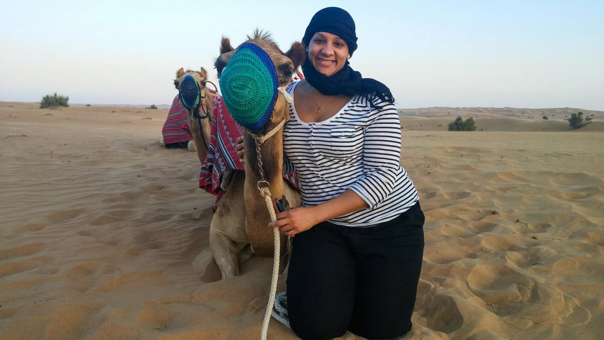 Photo of Ivory posing with a camel in the desert