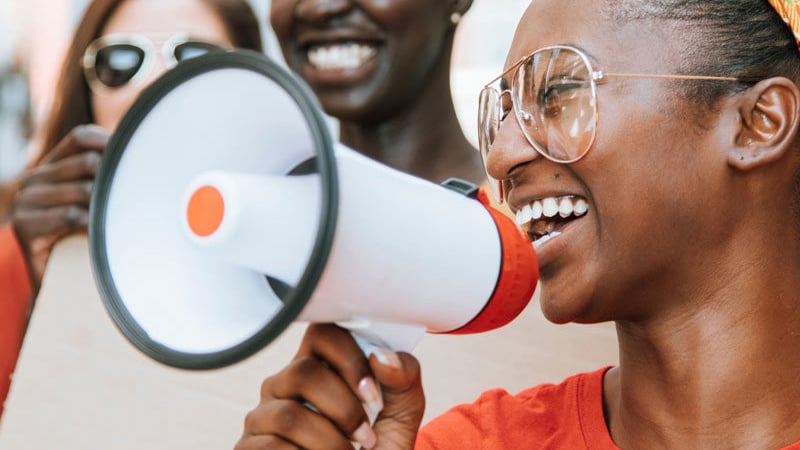 Smiling young woman, speaking into bullhorn
