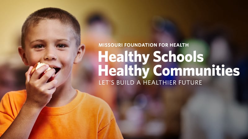 boy eating an apple in school next to superimposed logo of Healthy Schools Healthy Communities