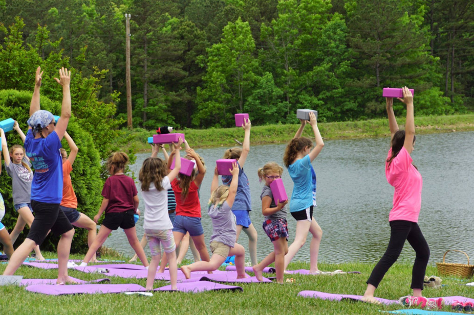 Children exercising with foam blocks outdoors by a pond