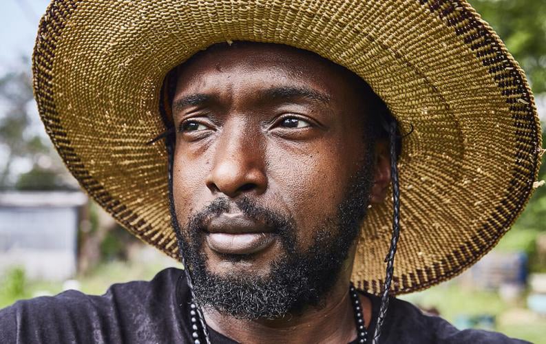Heru Lewis portrait with sunhat looking off at fields around him