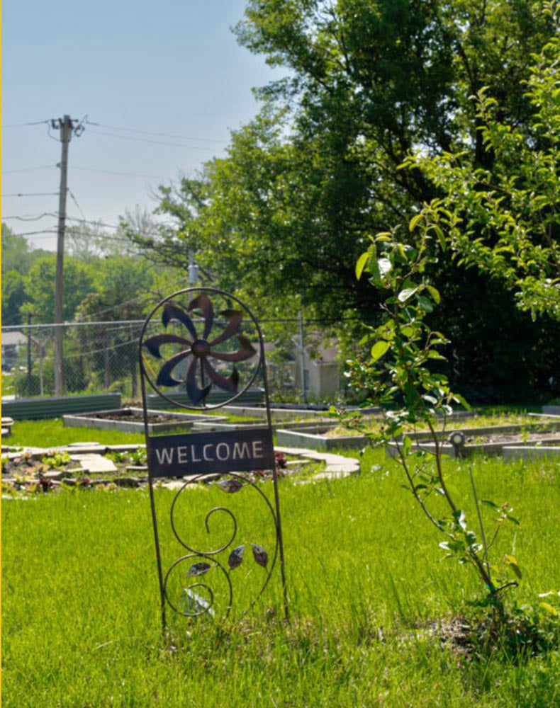 Welcome sign in community garden with young tree growing