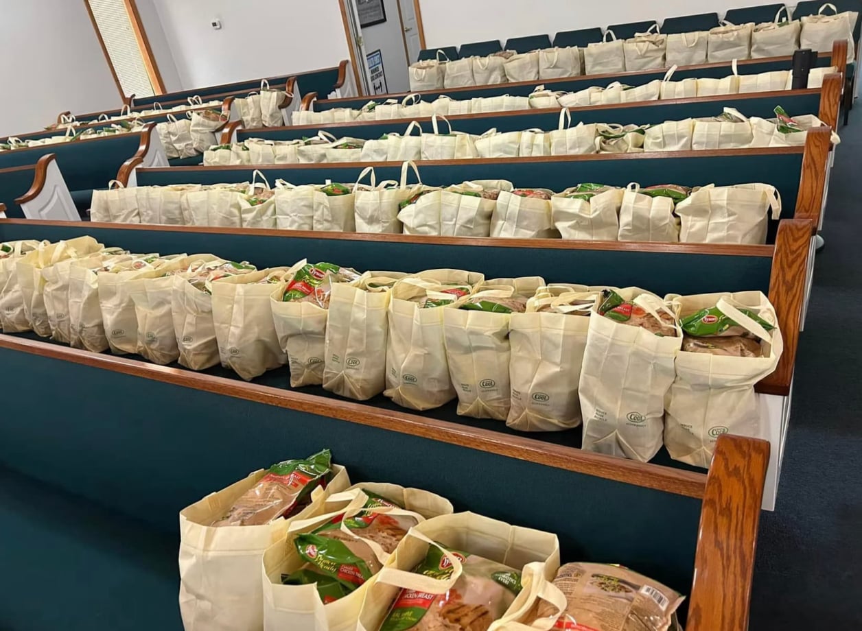 Rows of pews filled with tote bags of fresh produce and food to give away