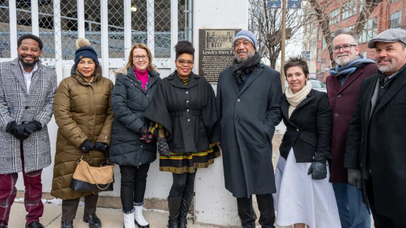 people standing in front of bronze plaque