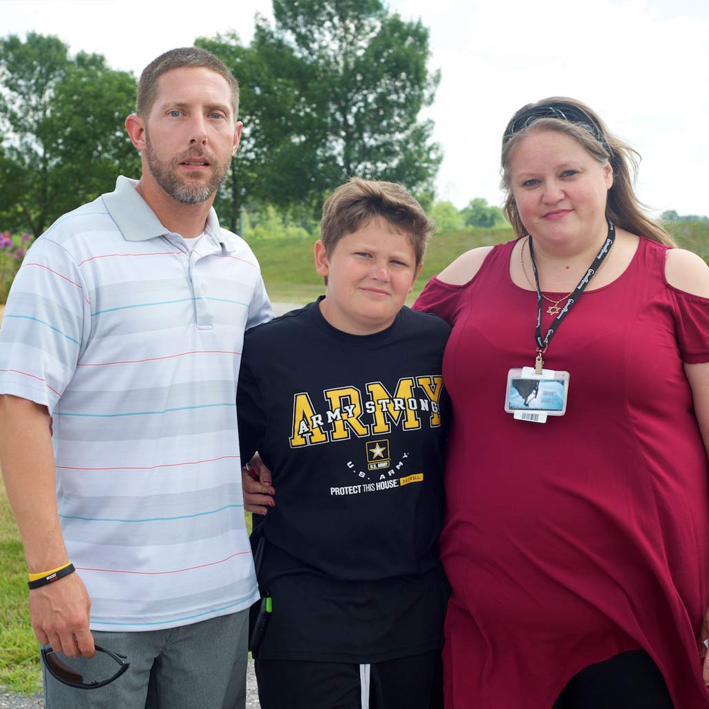 photo of mother, father and middle-school age son standing outdoors
