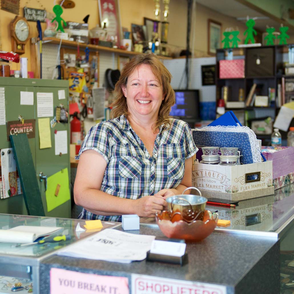 Woman standing behind counter of small resale shop