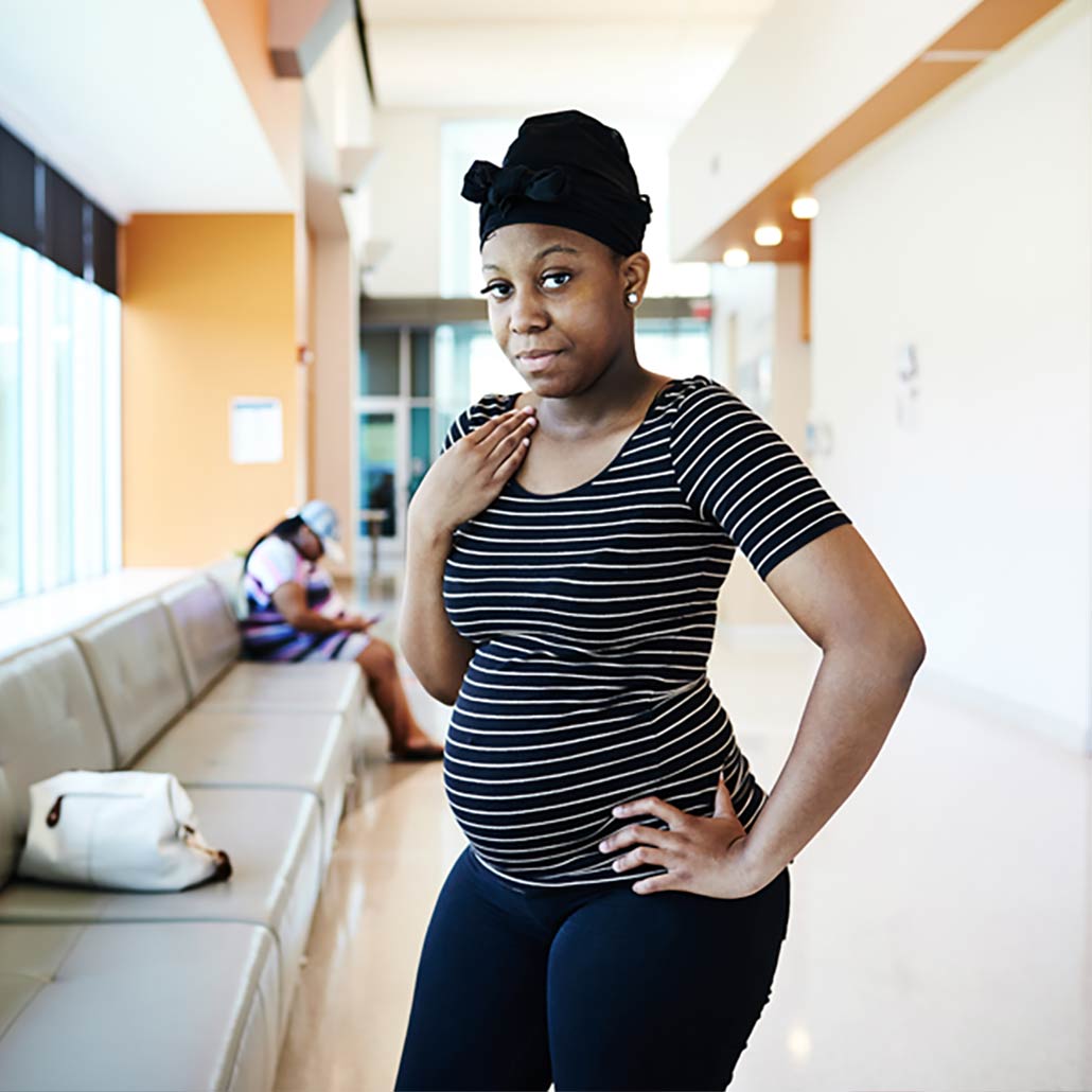 Photo of young, pregnant, Blak woman standing in medical facility