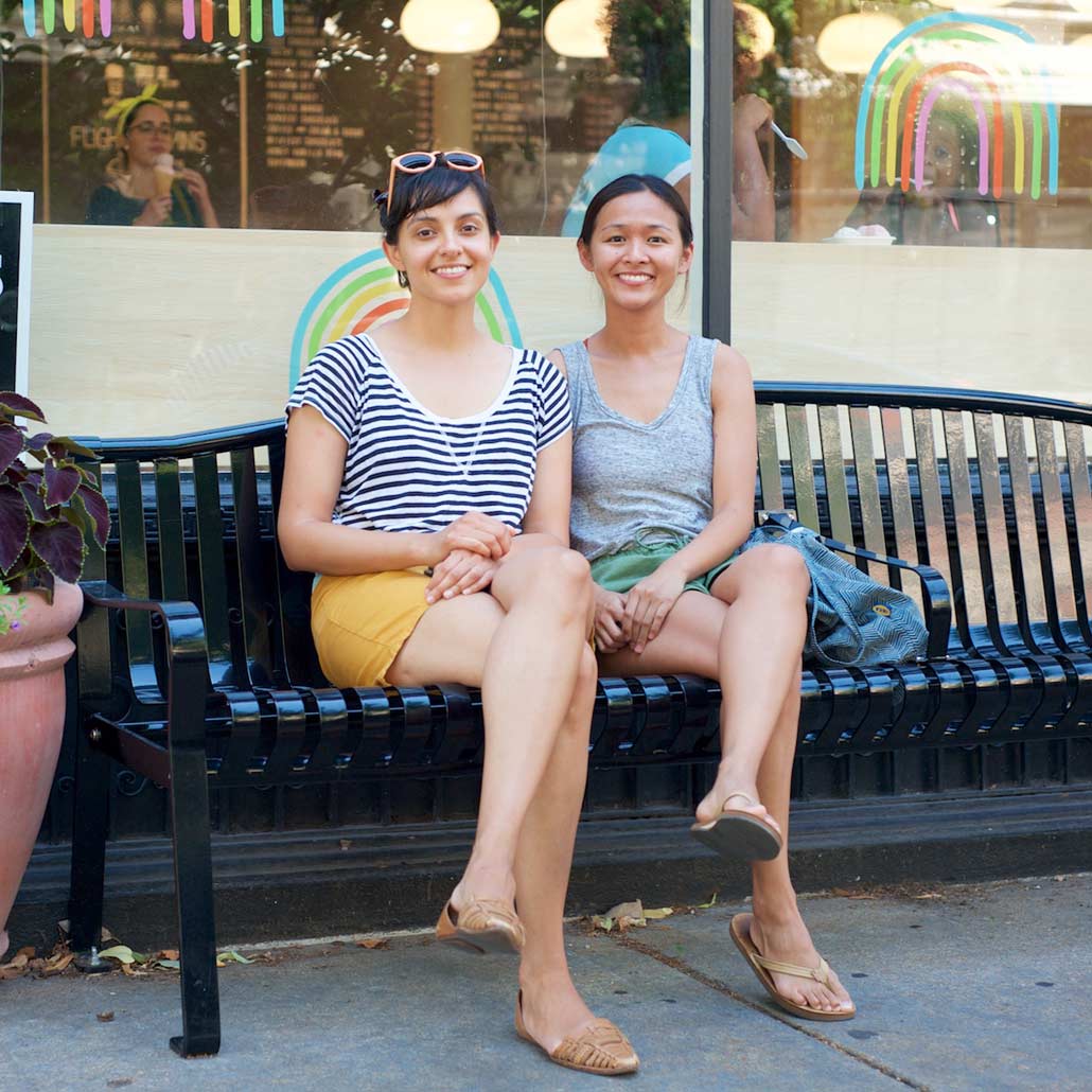 Photo of two young women hanging out on bench in front of restaurant