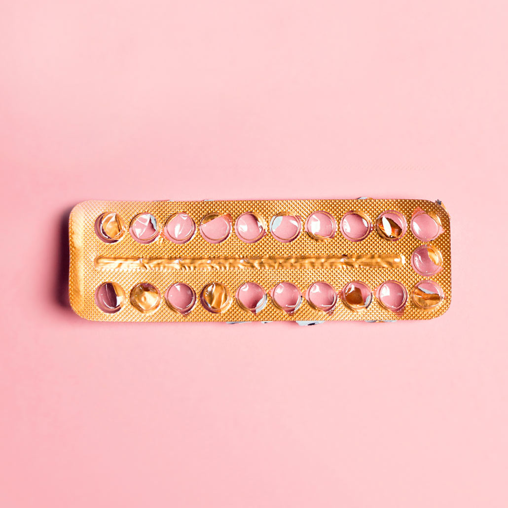 Photo of empty birth control pill package over pink background