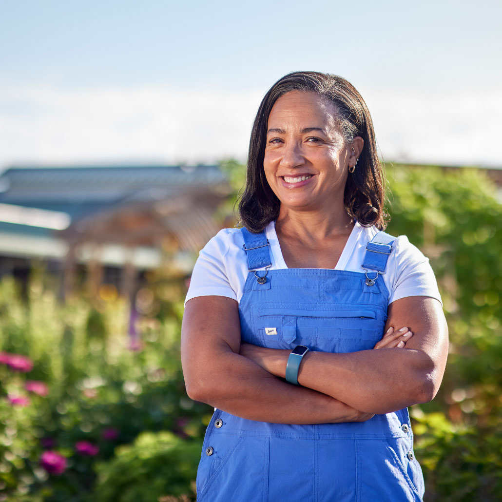 Woman smiling, arms folded in front of urban agriculture background